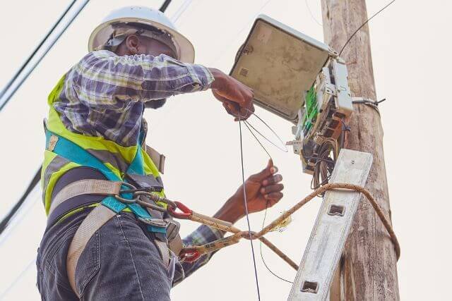 Technicien EagleVision installant un boîtier de fibre optique sur un poteau